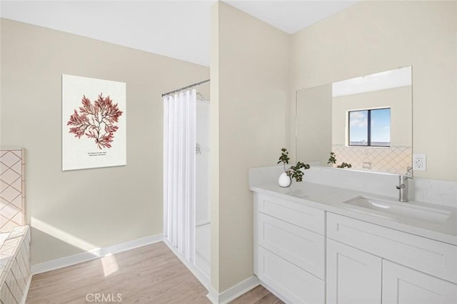 full bathroom with a shower with shower curtain, wood finished floors, vanity, and baseboards