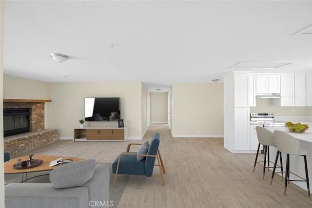 living room with light wood-style floors, a fireplace, and baseboards