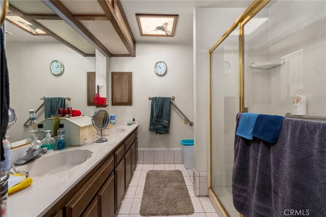 full bath with tile patterned flooring, a sink, baseboards, a shower stall, and double vanity