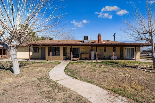 view of front of property with a chimney, cooling unit, and a patio