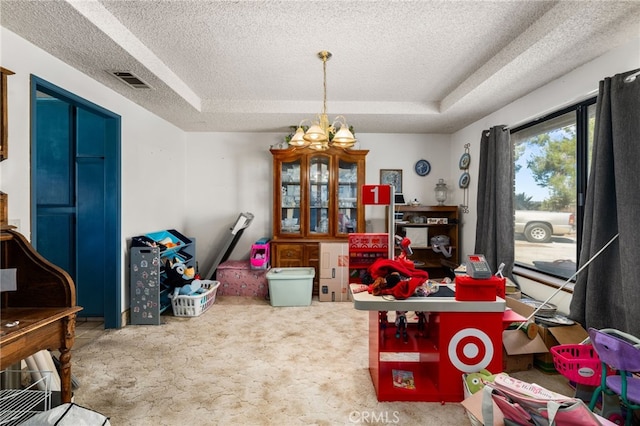 carpeted dining room with visible vents, a raised ceiling, a textured ceiling, and a chandelier