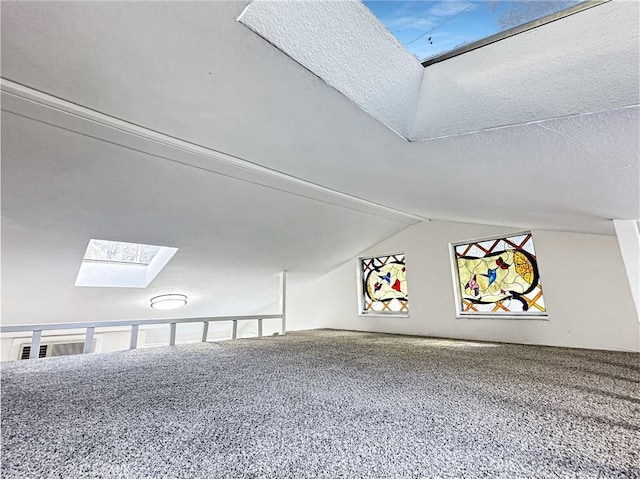 additional living space featuring a textured ceiling, vaulted ceiling with skylight, and carpet floors