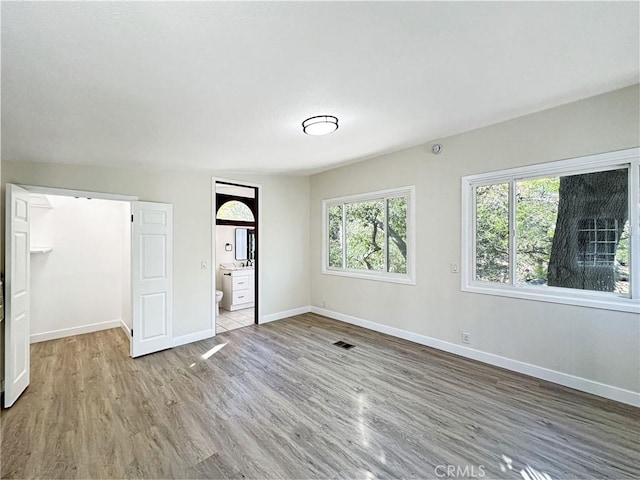 spare room with baseboards, visible vents, and wood finished floors