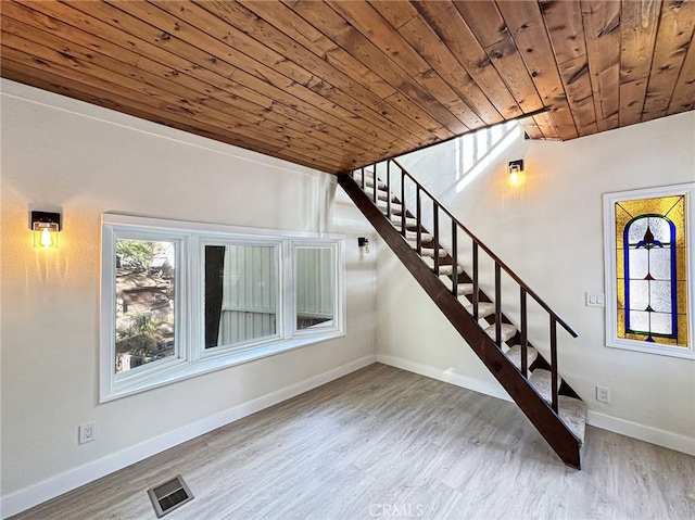 foyer featuring visible vents, wood finished floors, wooden ceiling, baseboards, and stairs