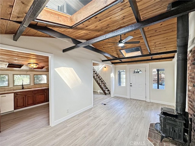 foyer entrance featuring a wood stove, light wood-type flooring, wood ceiling, and stairs