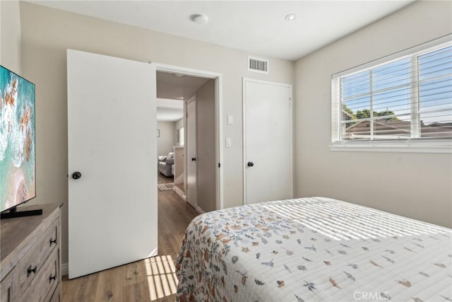 bedroom with light wood-style flooring and visible vents