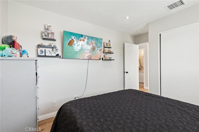 bedroom with a closet, visible vents, and light wood-style floors