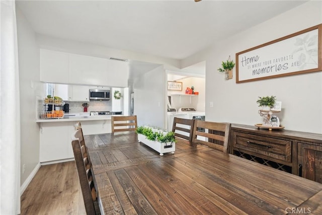 dining space featuring dark wood-style floors, visible vents, baseboards, and separate washer and dryer