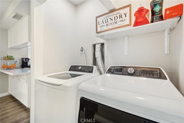 washroom featuring laundry area, visible vents, washing machine and clothes dryer, and wood finished floors