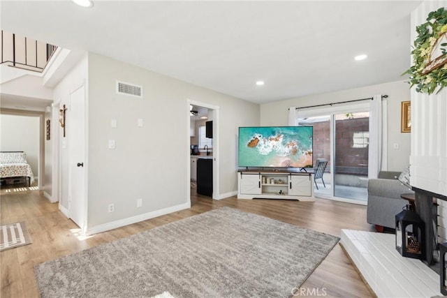 living room with recessed lighting, visible vents, baseboards, and wood finished floors