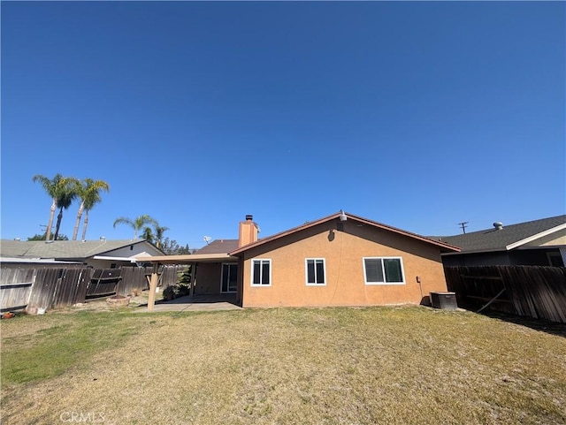 rear view of house with central AC, a lawn, fence, and stucco siding