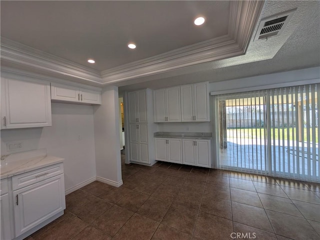 kitchen with crown molding, a tray ceiling, visible vents, and white cabinetry