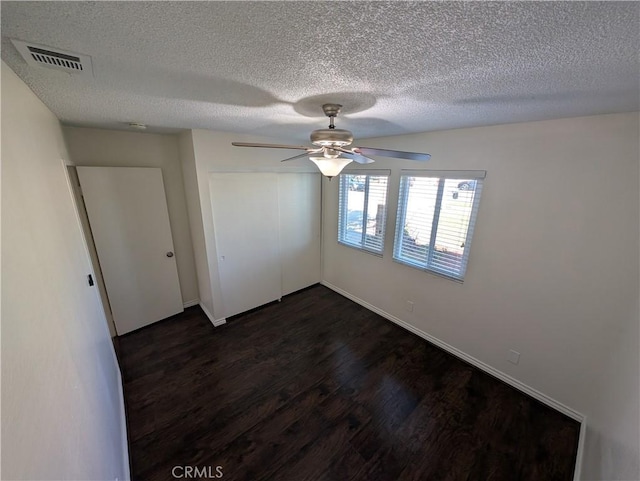 unfurnished bedroom featuring visible vents, dark wood-style floors, ceiling fan, a textured ceiling, and a closet