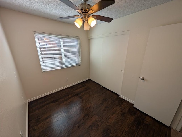 spare room featuring a textured ceiling, dark wood finished floors, a ceiling fan, and baseboards