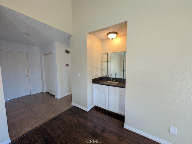 bathroom featuring a textured ceiling, vanity, baseboards, and wood finished floors