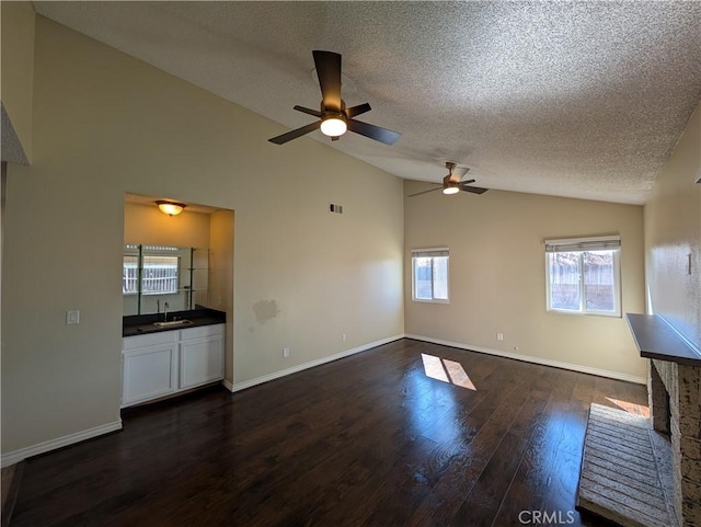 unfurnished living room featuring vaulted ceiling, baseboards, a sink, and dark wood-style floors