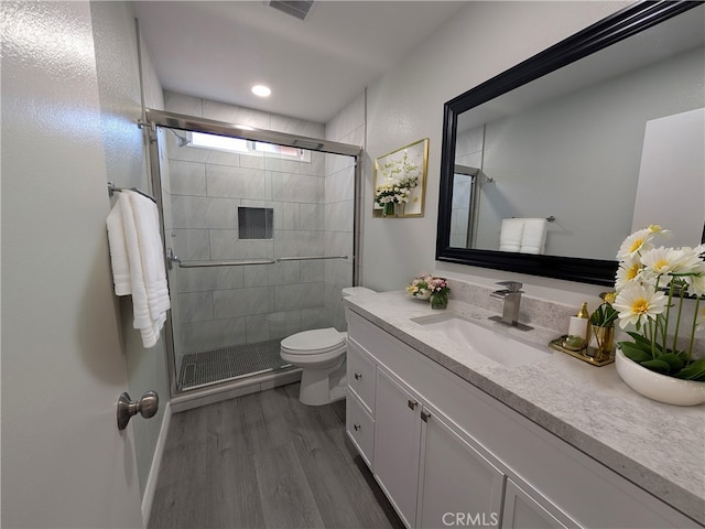 bathroom featuring visible vents, toilet, vanity, a shower stall, and wood finished floors