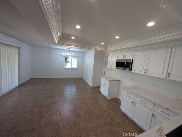 kitchen featuring recessed lighting, white cabinetry, ornamental molding, a tray ceiling, and stainless steel microwave