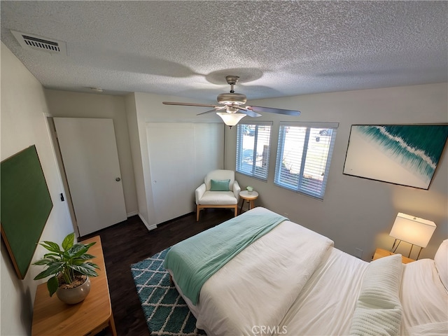 bedroom featuring visible vents, a ceiling fan, wood finished floors, a textured ceiling, and a closet