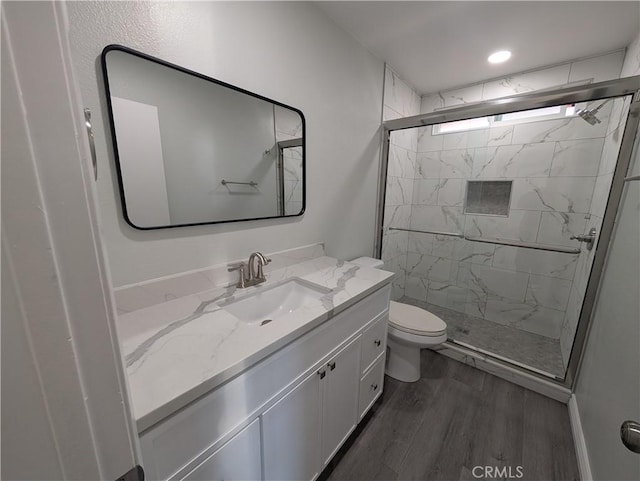 full bath featuring a stall shower, vanity, toilet, and wood finished floors