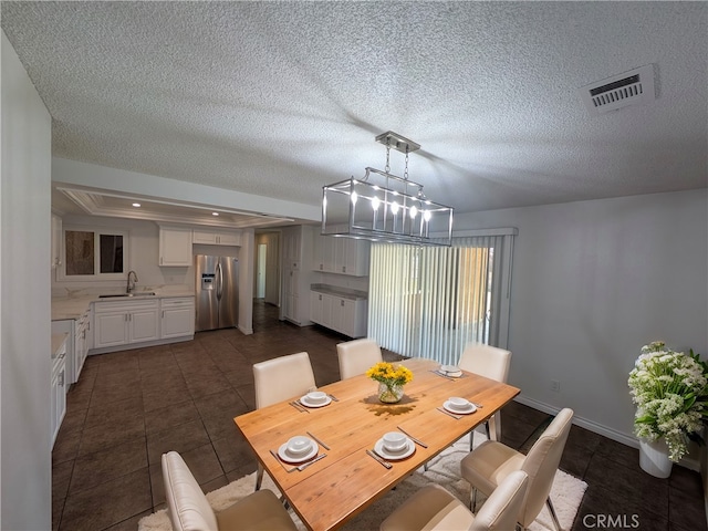 dining space with dark tile patterned flooring, visible vents, and a textured ceiling