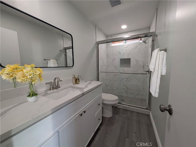 full bathroom featuring vanity, wood finished floors, a marble finish shower, and visible vents