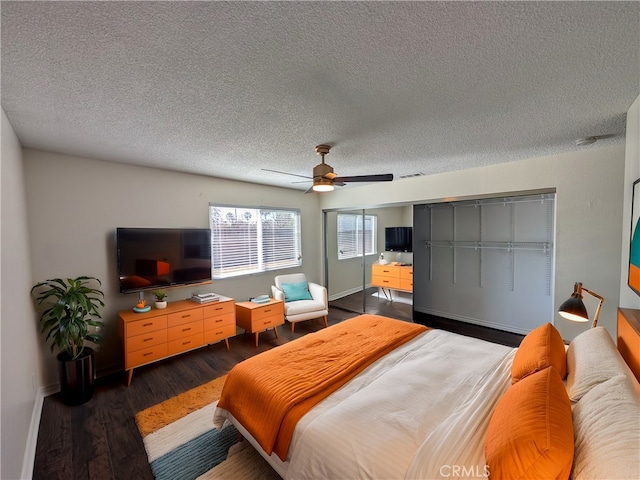 bedroom featuring dark wood-style flooring, visible vents, ceiling fan, and a textured ceiling