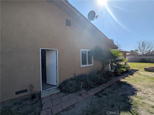 back of property with a lawn, fence, and stucco siding