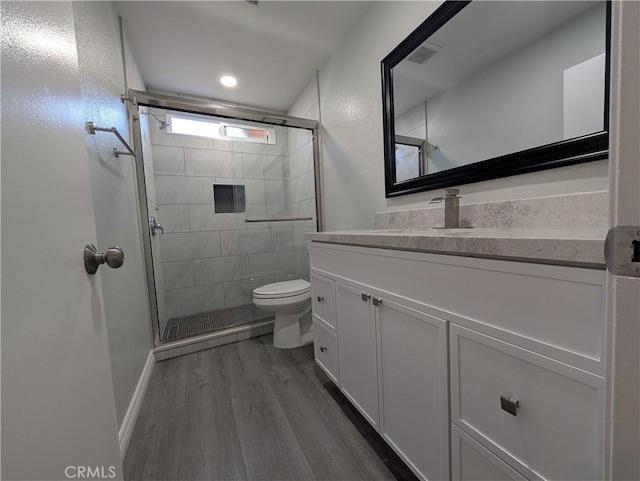 full bathroom featuring vanity, a shower stall, toilet, and wood finished floors