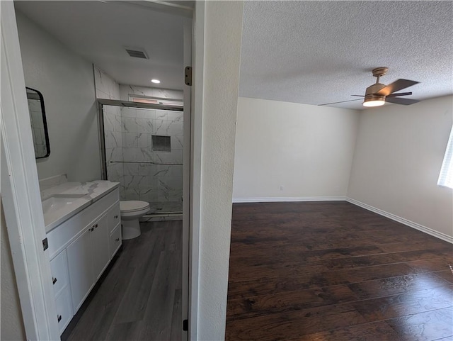 bathroom featuring a marble finish shower, a textured ceiling, baseboards, and wood finished floors