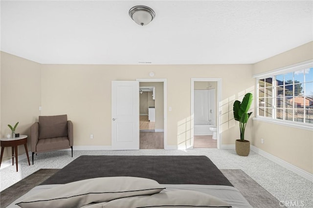 bedroom featuring connected bathroom, baseboards, and carpet flooring