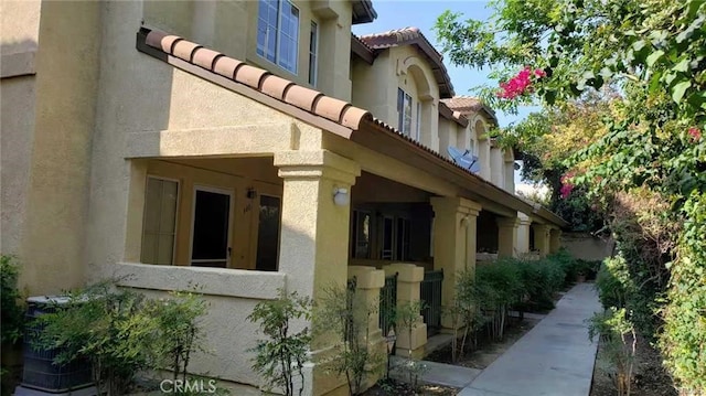 view of side of home with a tiled roof and stucco siding