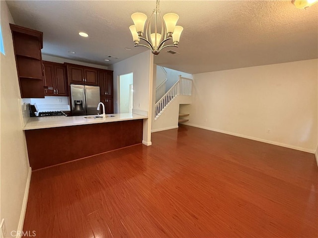 kitchen featuring range with gas stovetop, open shelves, a sink, wood finished floors, and stainless steel fridge