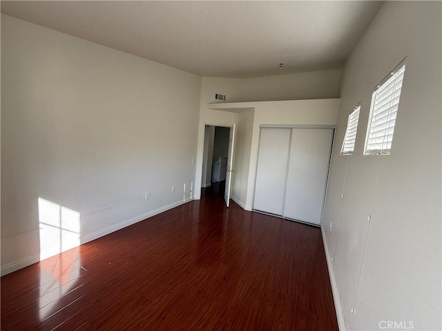 unfurnished bedroom with a closet, baseboards, and wood finished floors