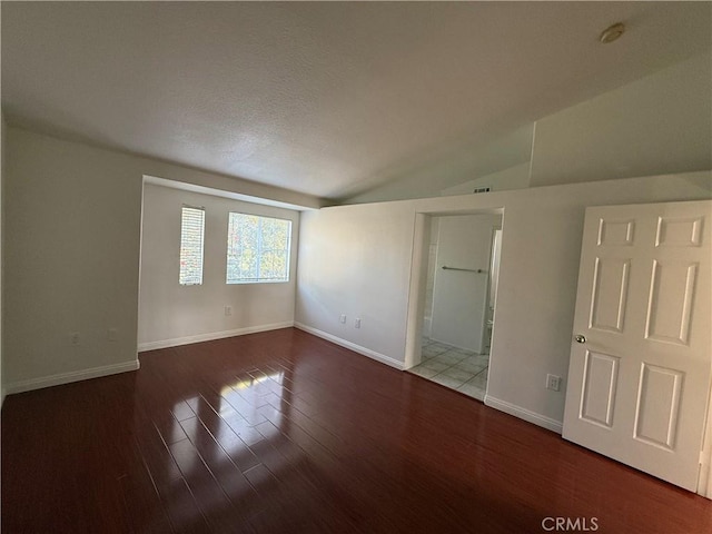 unfurnished room with visible vents, baseboards, vaulted ceiling, and wood finished floors