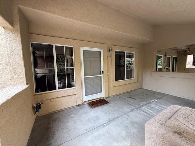 view of exterior entry with stucco siding and a patio