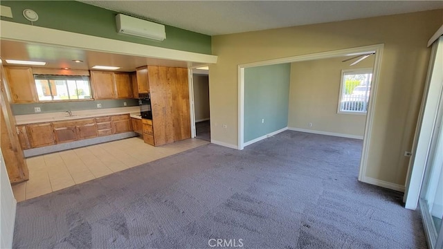 kitchen with light colored carpet, baseboards, light countertops, brown cabinets, and a wall mounted air conditioner