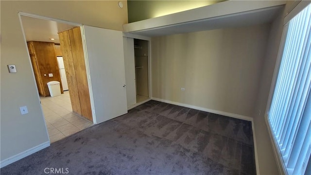 unfurnished bedroom featuring tile patterned flooring, a closet, carpet flooring, and baseboards