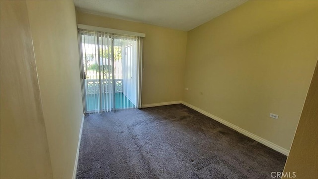 unfurnished room featuring dark colored carpet and baseboards