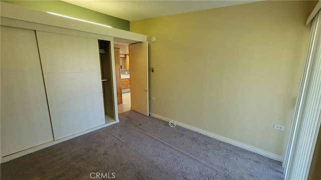 unfurnished bedroom with carpet floors, a closet, and baseboards