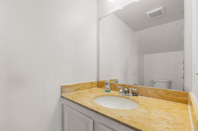 bathroom with toilet, visible vents, and vanity