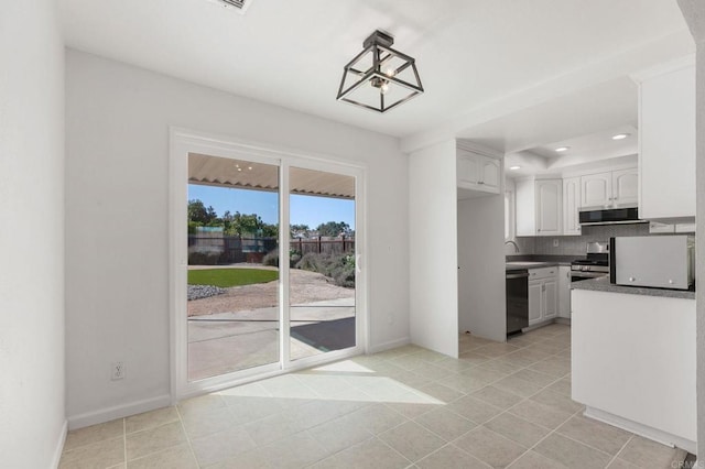 kitchen with tasteful backsplash, dark countertops, appliances with stainless steel finishes, white cabinetry, and a sink