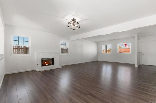 unfurnished living room with a fireplace, baseboards, and dark wood finished floors