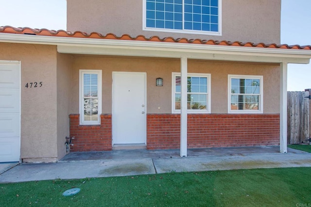 doorway to property with a garage, stucco siding, and brick siding