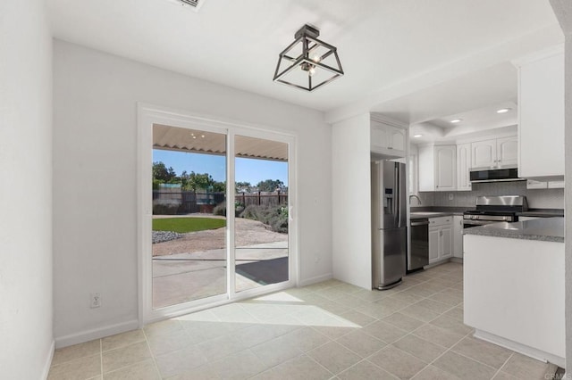 kitchen featuring stainless steel appliances, dark countertops, tasteful backsplash, white cabinetry, and baseboards