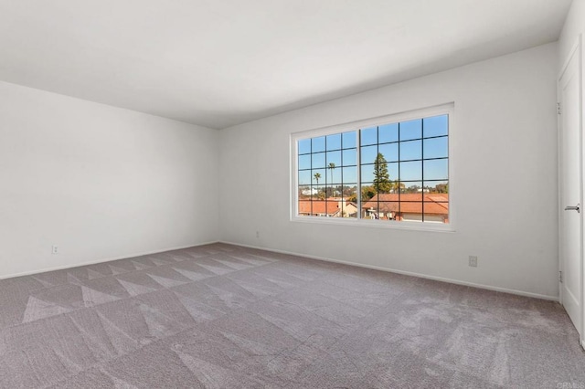 carpeted spare room featuring baseboards