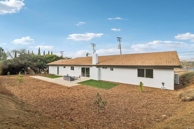 back of property with a tile roof, a patio area, and stucco siding