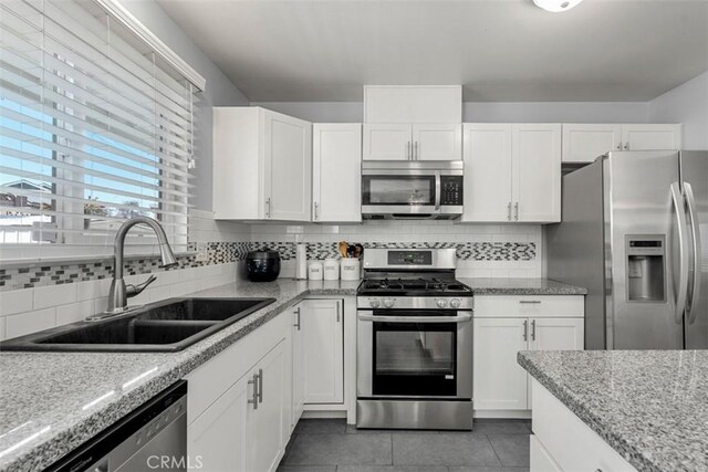 kitchen featuring appliances with stainless steel finishes, a sink, white cabinetry, and tasteful backsplash