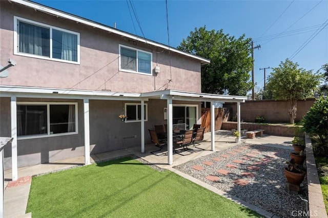 back of house with a yard, a patio area, fence, and stucco siding