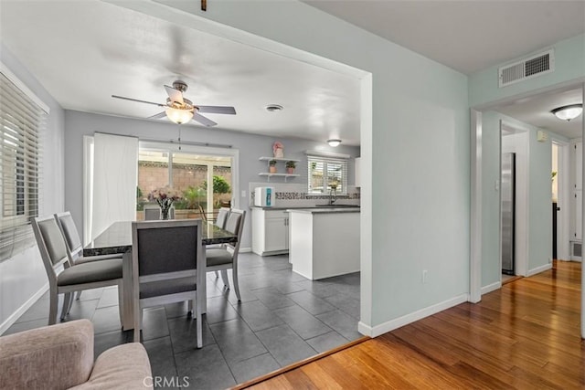 dining space featuring a ceiling fan, dark wood-style flooring, visible vents, and baseboards